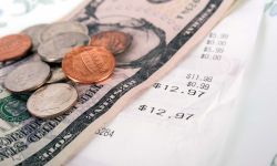 Restaurant bill with dollar bills (tips) on a plate and receipt close up