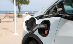 White EV car being charged at the beach