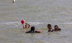 Kids swimming and playing in the water. One of the kids have a ball