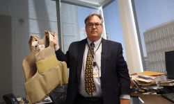 Tom Liddy holding up a bulletproof vest 