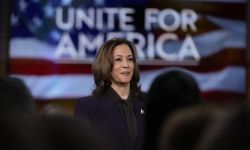 Vice President Kamala Harris stands in front of a screen that says "Unite for America" 