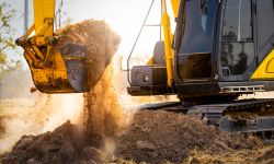 Close-up of excavator at construction site. Backhoe digging soil for earthwork and construction business. Excavating machine at work. Heavy machinery for earth moving and construction site development