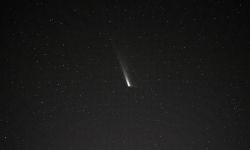 A comet, which looks like a white burst of light, at the dark sky