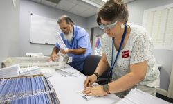 Dawn Stephens, right, and Duane Taylor preparing ballots on a white table