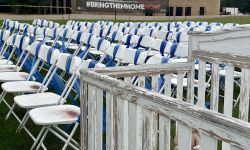 Rows of empty chairs. The chairs have blue ribbons 