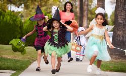 Parent Taking Children Trick Or Treating At Halloween