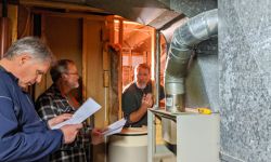 Three men look at a furnace 