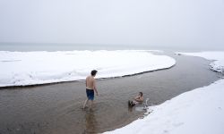 Two people in East Bay of Grand Traverse Bay in Michigan. It's snowy and icy outside. 