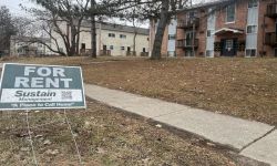 A sign that says "For Rent" in front of an apartment.