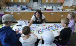 Becca Bradley sits at a table while interacting with students. 