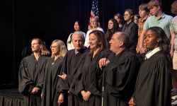 Michigan Supreme Court justices stand in a row. Students are behind them.