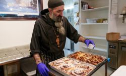 A man sprinkles powdered sugar over panfuls of pastries