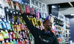 A man reaches up to grab a product from a wall full of marijuana products