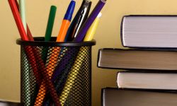 stock image of books and a cup filled with pens in a classroom